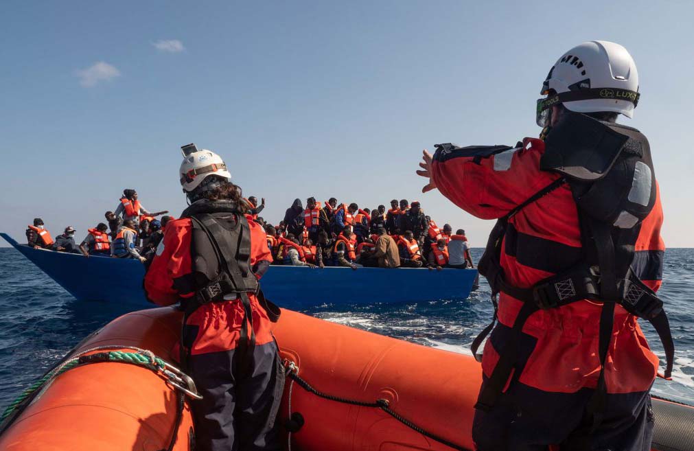 migrants on boat being rescued from the sea