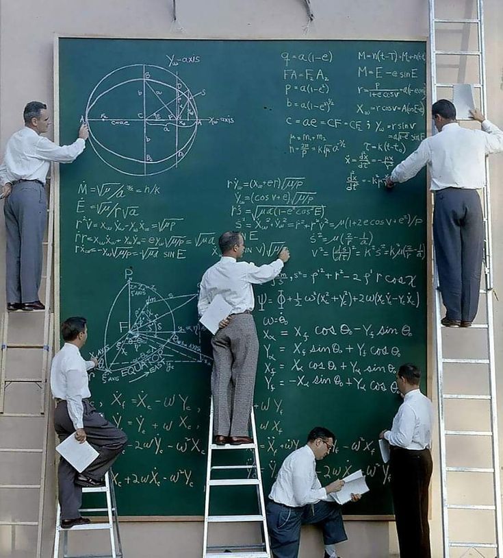 NASA Mathematicians working on a large chalk board, some on ladders