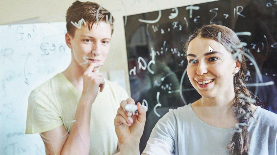 Young mathematicians writing on a glass panel